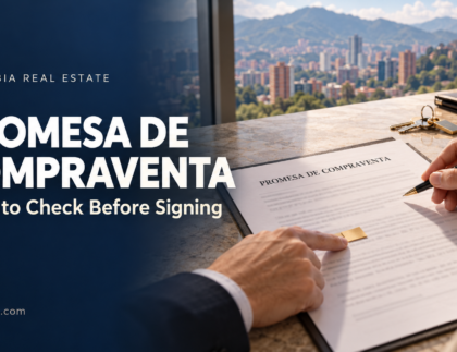 Hands reviewing a Colombian promesa de compraventa beside property keys, with Medellín in the background.